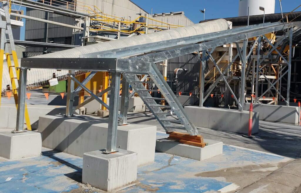 A steel structure with Belt Conveyors in front of it.