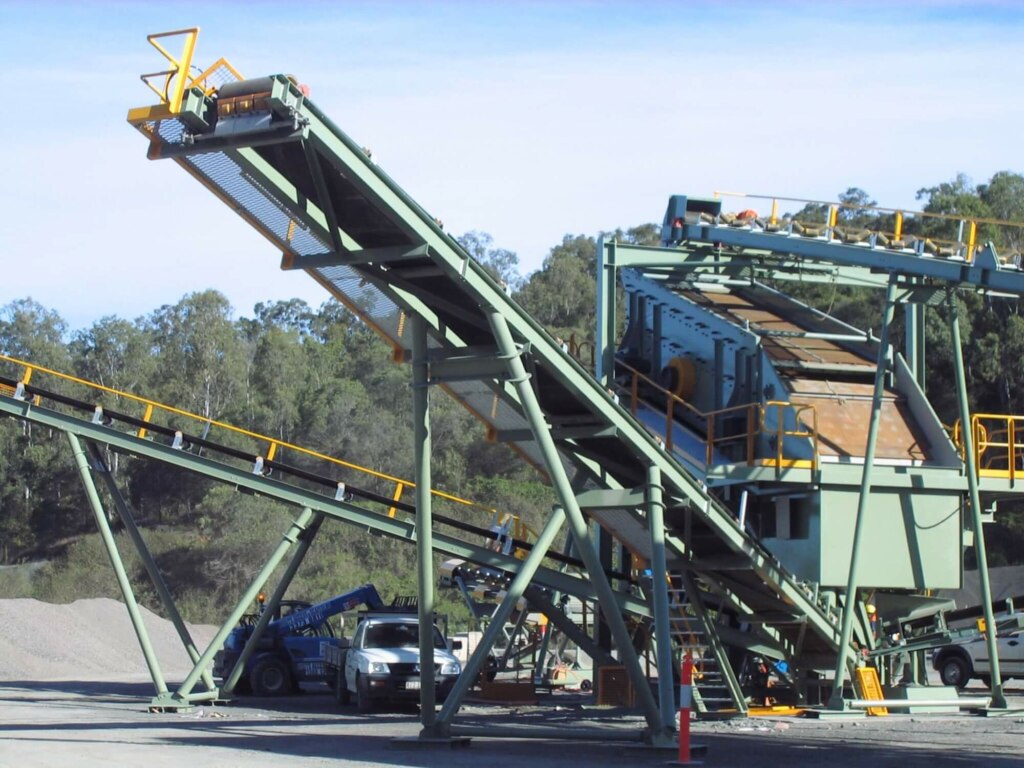 A truck stands in front of a massive conveyor belt.