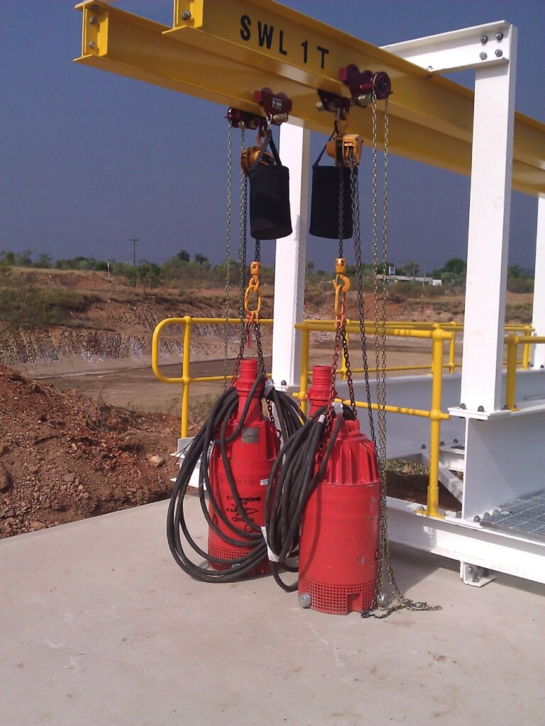 A crane undergoes a Raw Water System Upgrade with two red hoses attached to it.