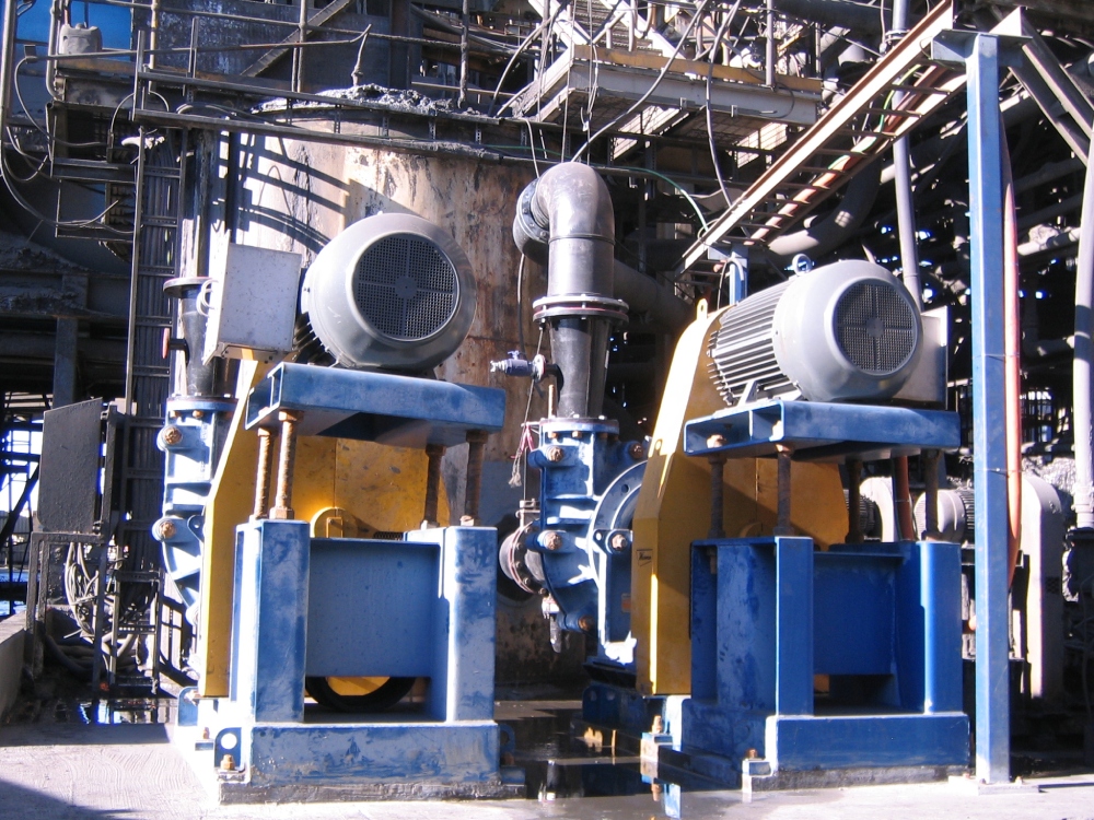 Two blue and yellow machines, one of them being a floatation pump, are positioned in front of a building undergoing a system upgrade.