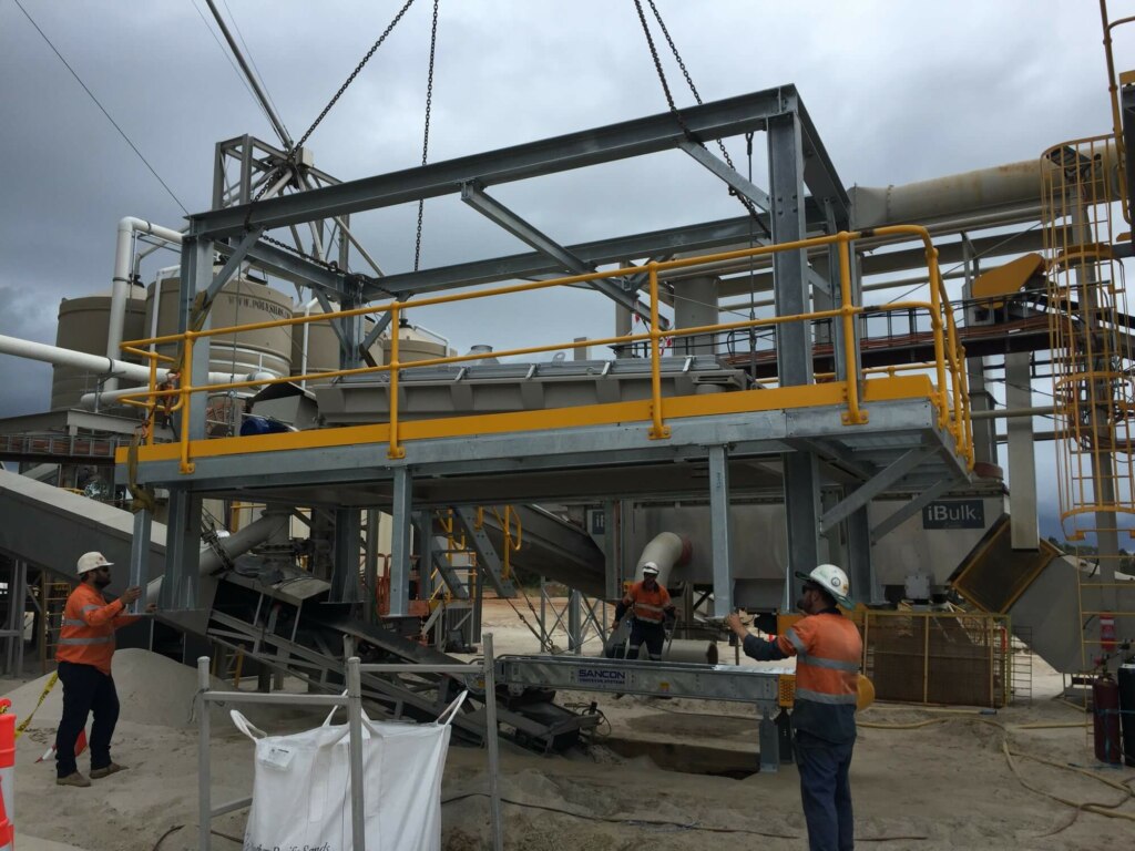 A group of workers are working at a Truck Loadout Facility construction site.
